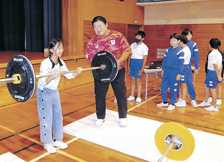 児童にバーベルを挙げる楽しさを伝える村上選手（左から２人目）＝富山市浜黒崎小