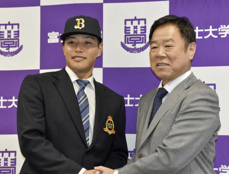 オリックスの福良GM（右）からドラフト1位指名のあいさつを受け、笑顔を見せる富士大の麦谷祐介外野手＝28日、岩手県花巻市