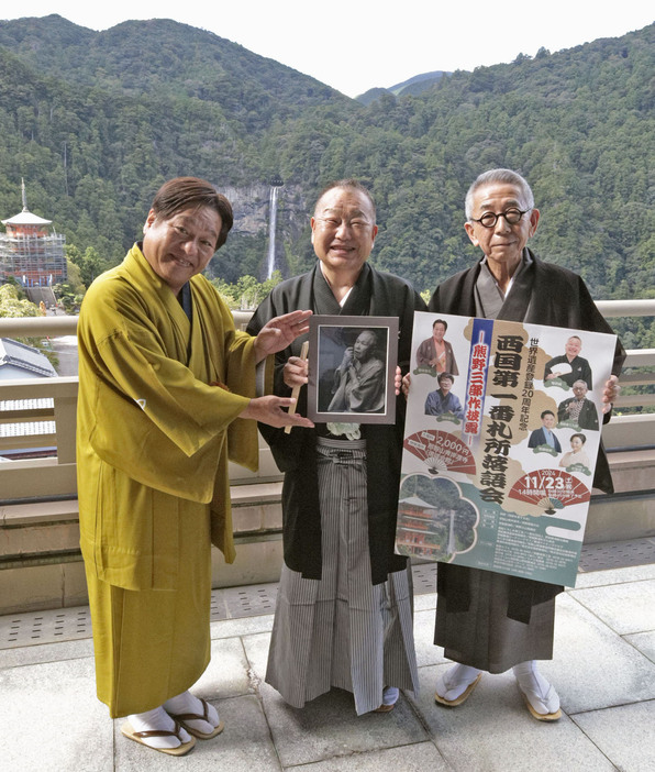 那智の滝をバックに落語会をアピールする（左から）桂枝曾丸さん、桂坊枝さん、熊野家三九郎さん＝9月、和歌山県那智勝浦町