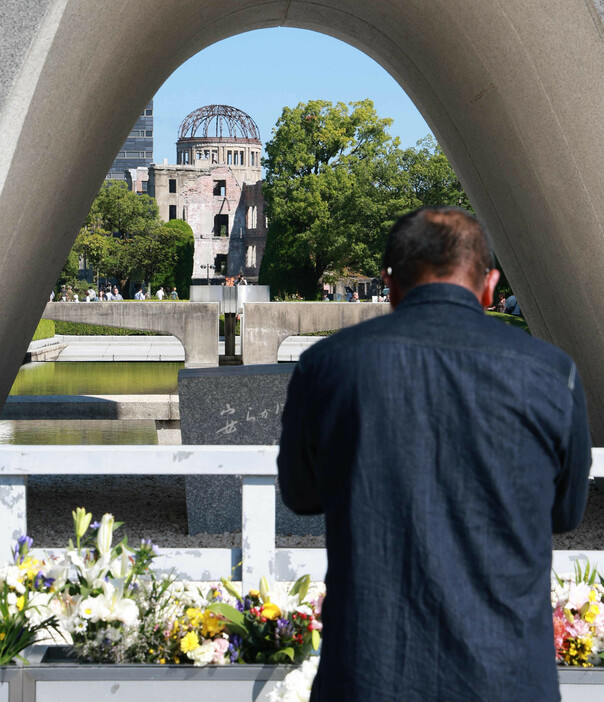 日本原水爆被害者団体協議会（日本被団協）のノーベル平和賞受賞の決定から一夜明け、平和記念公園で手を合わせる人＝１２日午前、広島市中区