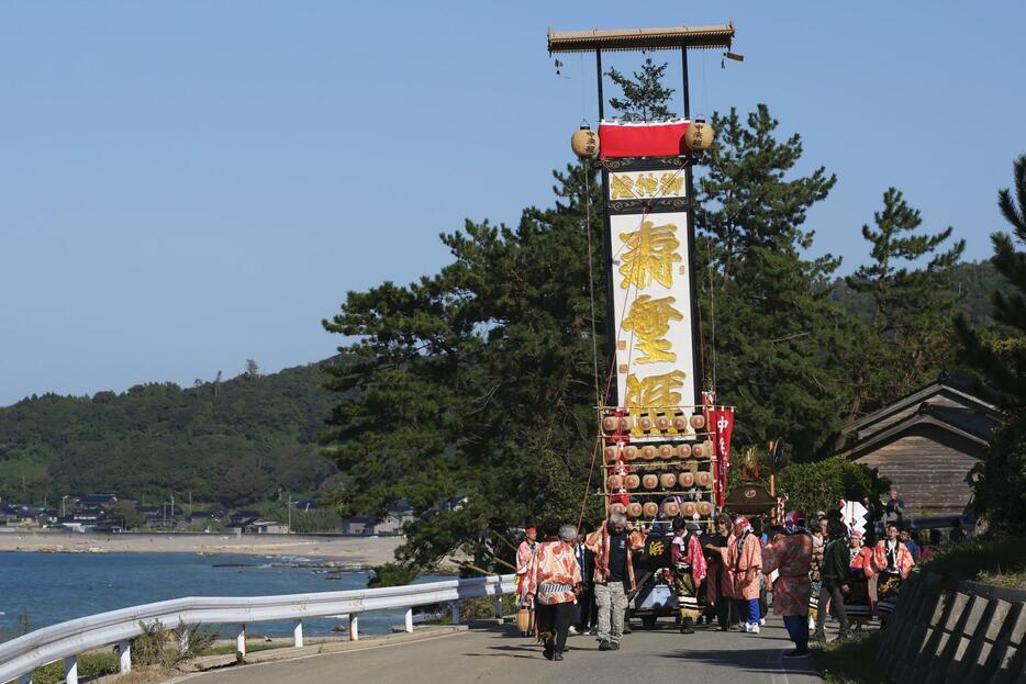 石川県珠洲市馬緤町で「馬緤キリコ祭り」が開かれ、地震と豪雨被害の爪痕が残る地区内を巡行する巨大な灯籠「キリコ」＝13日午後