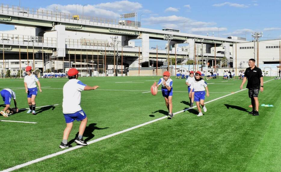 １８年ぶりに張り替えられた人工芝の上でラグビー体験を楽しむ子どもら＝神戸市東灘区御影浜町、コベルコスポーツパーク