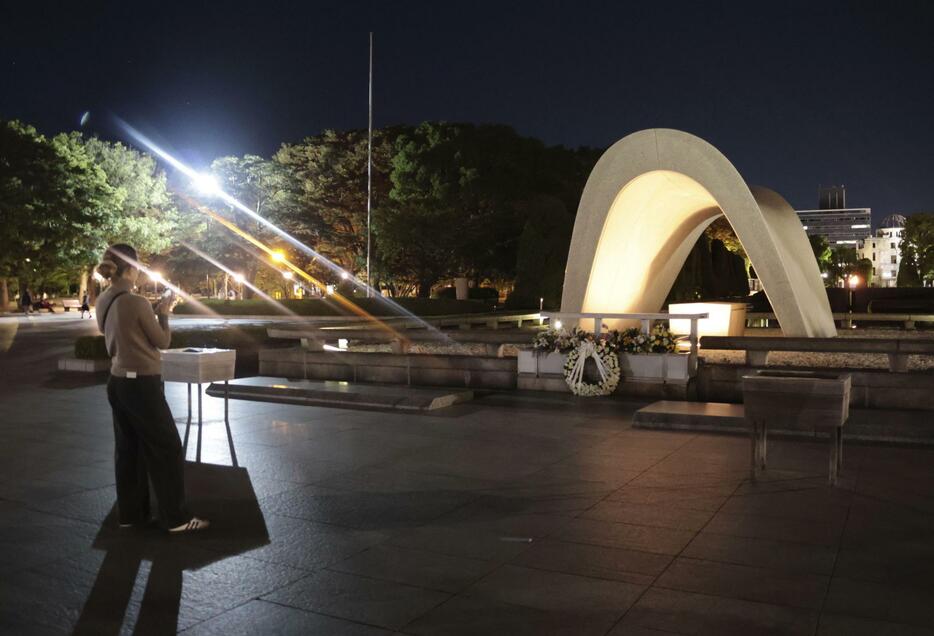 平和記念公園の原爆慰霊碑を訪れた外国人観光客。被団協のノーベル平和賞受賞が決まった＝11日午後7時57分、広島市