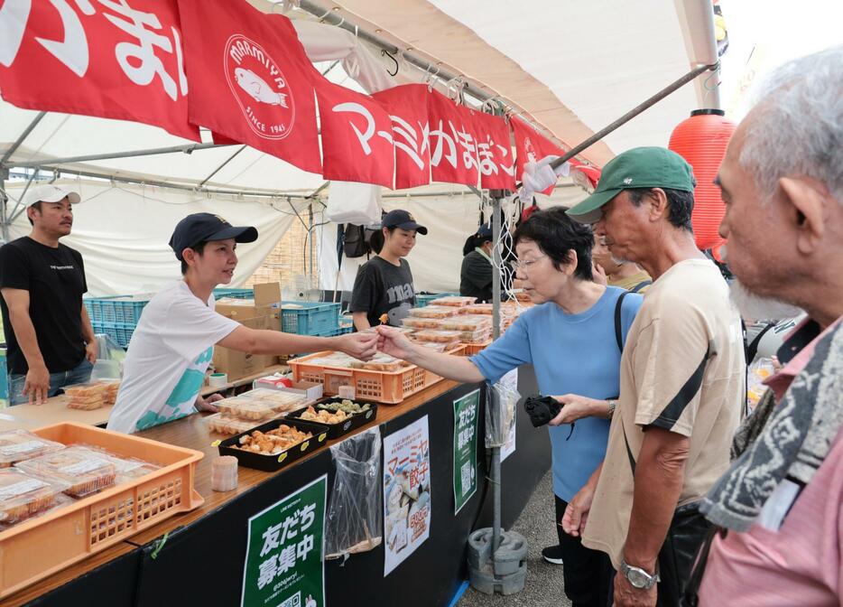 マーミヤかまぼこのブースで試食を楽しむ買い物客＝25日、那覇市の奥武山公園（大城直也撮影）