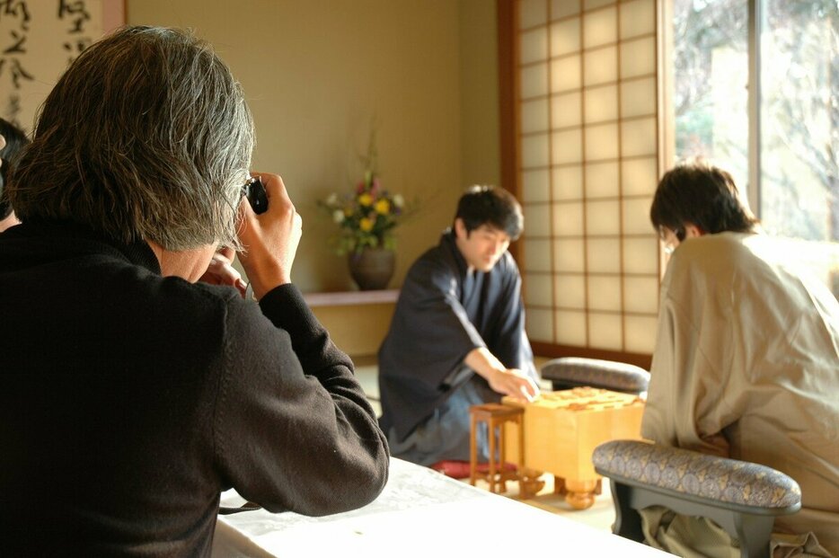 名カメラマン弦巻勝さん（写真左）。2005年1月、森内俊之王将－羽生善治挑戦者戦を撮影中（写真：松本博文）