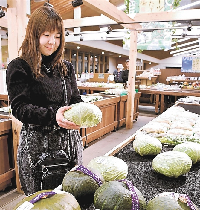 商業施設で野菜を手に取る赤坂さん。食費が膨らむ中、物価高対策に関心を寄せている