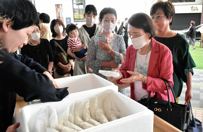 「御祝」の焼き印を入れたほっぺ焼きを受け取る買い物客ら＝１日、鳥取市今町２丁目の丸由百貨店前