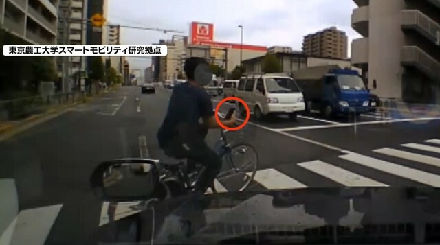 スマホを見ながら赤信号で横断歩道を渡る自転車利用者