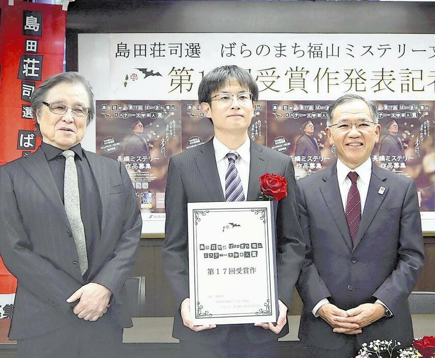 選者の島田荘司さん（左）と枝広直幹市長（右）から祝福される竹中さん（広島県福山市で）