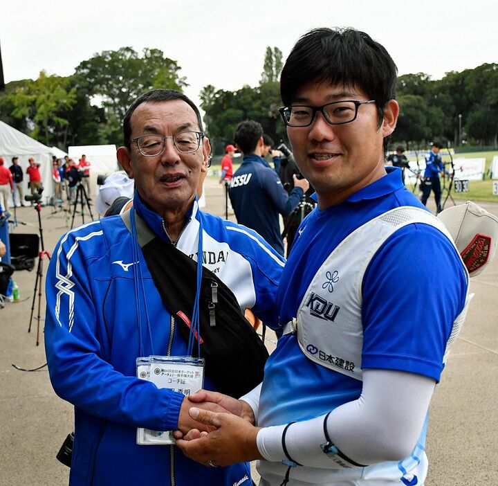 現役最後の試合を終え、近大の山田監督（左）と握手を交わす古川＝東京・夢の島公園アーチェリー場