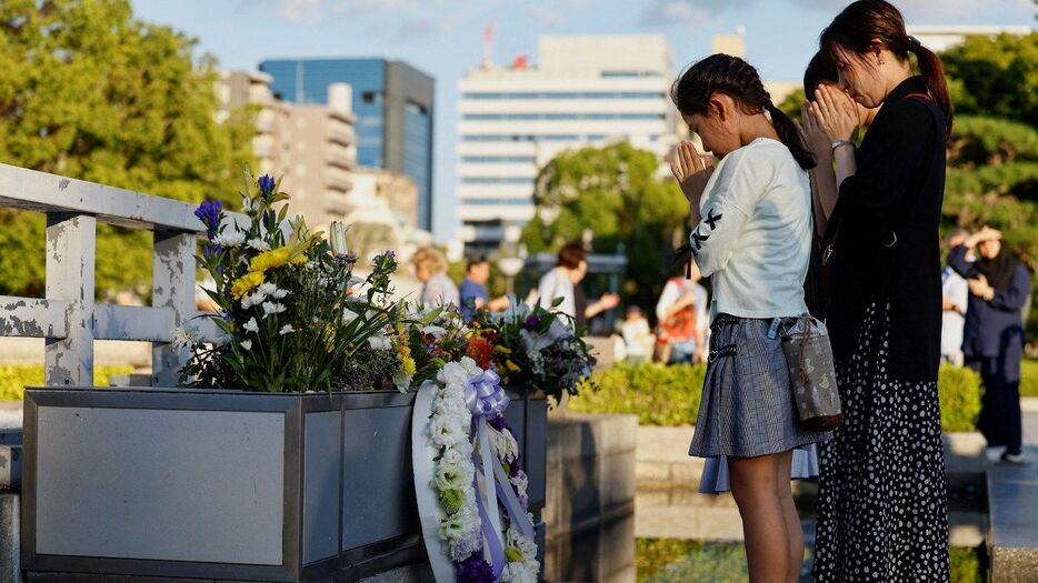 原爆死没者慰霊碑で手を合わせる人々（ロイター）