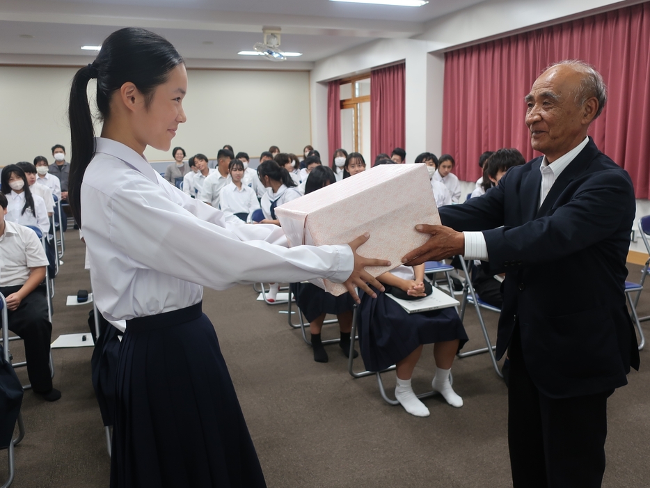 谷西会長から自転車用LEDライトを受け取る定森さん=岡山県津山市で