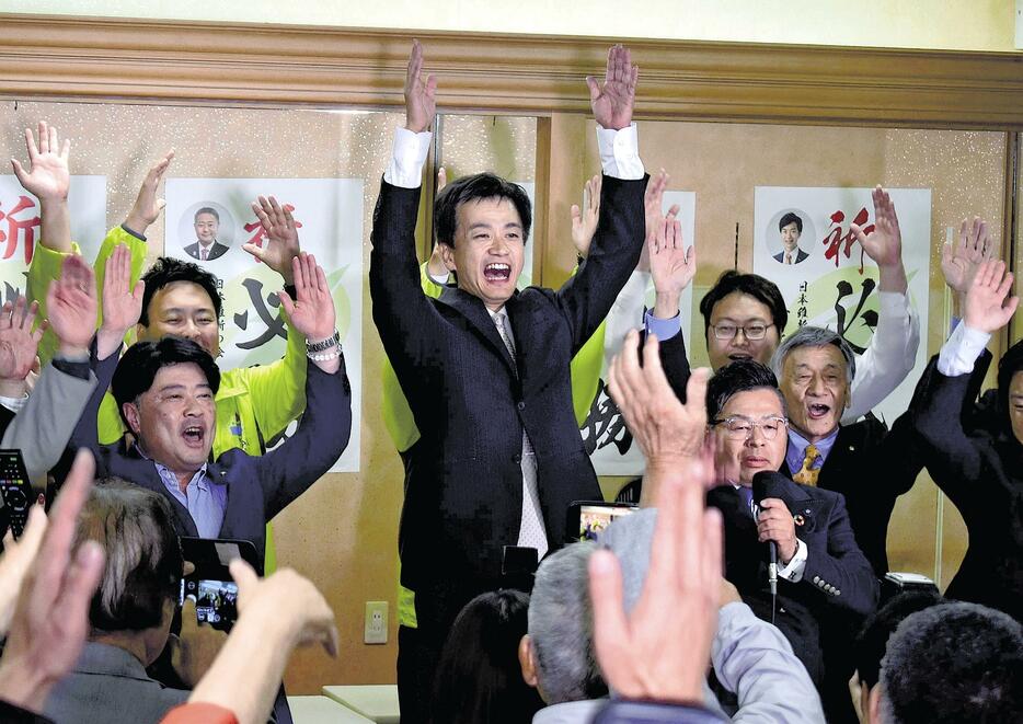 支援者と万歳をして初当選を喜ぶ村上さん（中央）