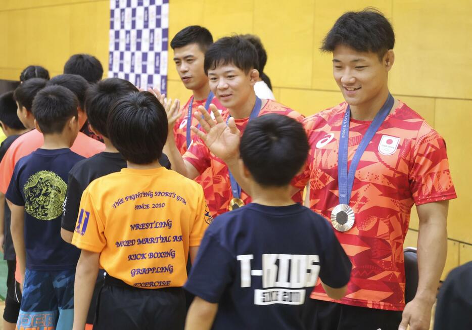 イベントで子どもたちと交流するレスリング男子の（右から）高谷大地、樋口黎、文田健一郎＝13日、東京都内