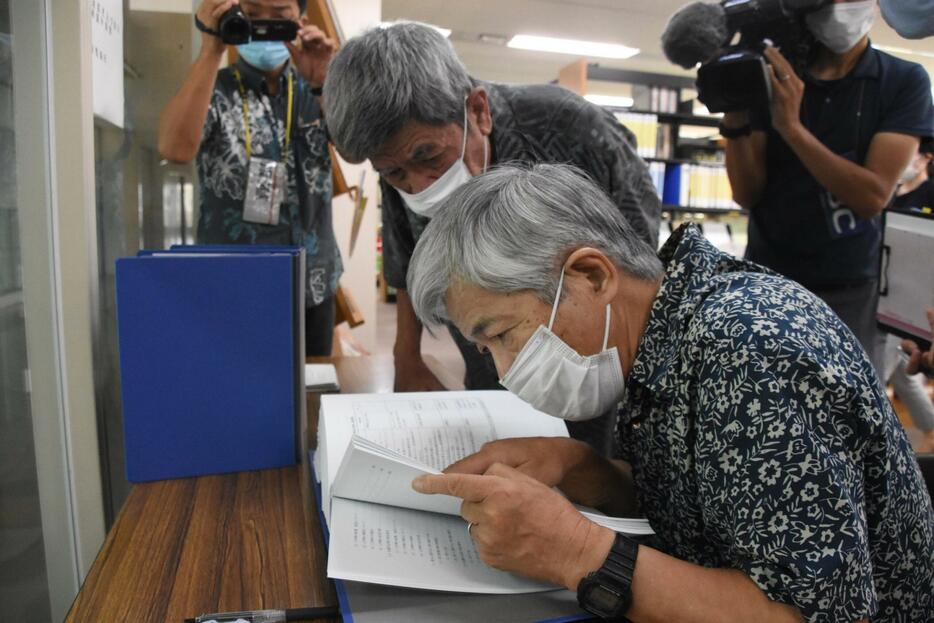 辺野古新基地建設をめぐり、公開された設計変更承認申請書を読む沖縄環境ネットワーク世話人の桜井国俊氏（手前）ら＝2020年9月、県庁