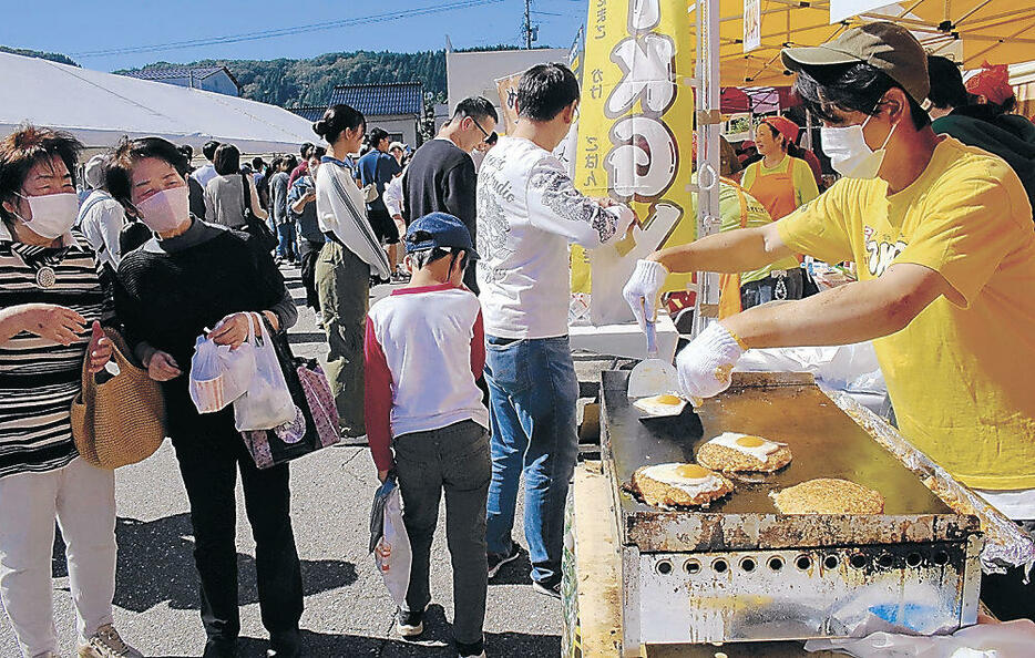 ご当地グルメを満喫する来場者=白山市の鶴来本町通り商店街