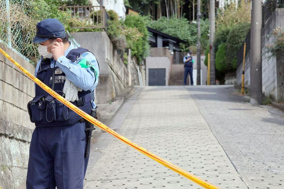 事件現場付近は規制線が張られ警察官が立っている＝17日午前、横浜市青葉区