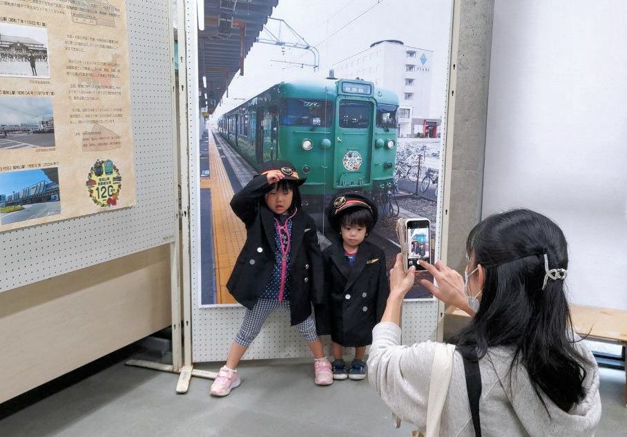 「なりきり駅長」の衣装を着て記念撮影を楽しむ親子（綾部市里町・市天文館パオ）