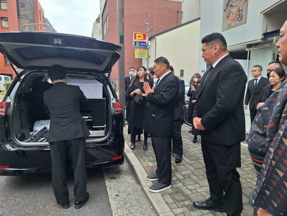 元旭国の太田武雄さんの棺の乗った霊きゅう車に手を合わせる元旭鷲山のダヴァー・バトバヤルさん（中央）、大島親方（右）