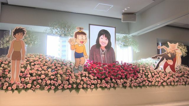 バラの花と小原さんが演じてきたキャラクターのパネルが飾られた祭壇