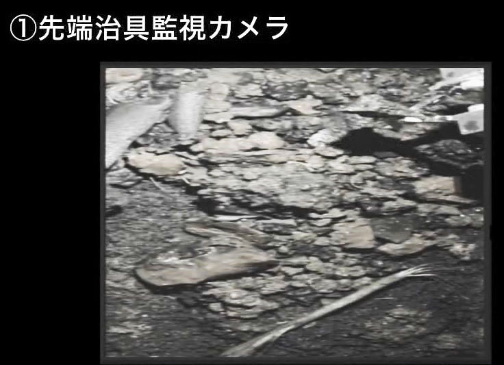 原子炉格納容器の底部に広がる小石状のデブリの一つを爪形装置（右上）でつかんで持ち上げる様子＝9月14日（東京電力提供）