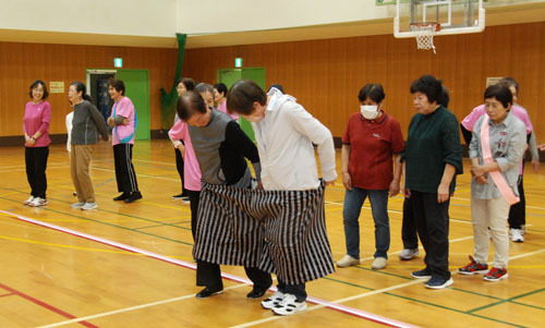 【和気あいあいと「でかパンリレー」競技を楽しむ参加者ら＝亀山市野村2丁目の市西野公園体育館で】