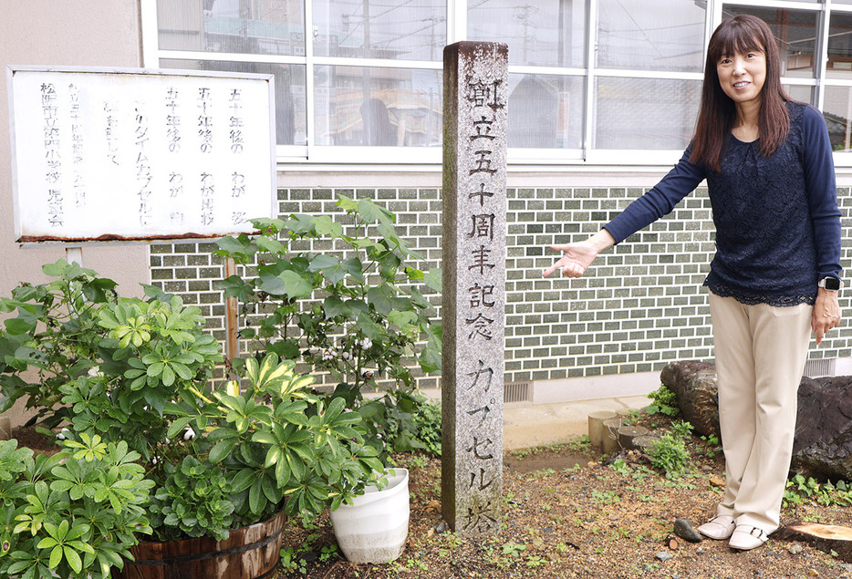 タイムカプセルが埋められた場所を示す中西校長。石碑と看板もある ＝鎌田町の第四小で