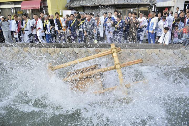 豪快に川へ投げ込まれ大きな水しぶきを上げるみこし＝14日午後、松山市北条辻