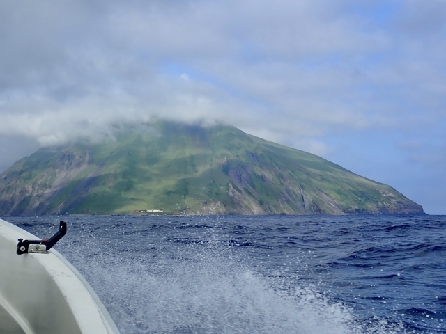 しだいに近づいてくる渡島大島。頂部は雲に覆われている。島にある白い建物は漁船避難用の港　photo by Fukashi Maeno