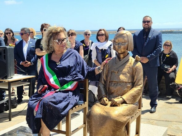 今年6月22日（現地時間）、イタリアのサルディーニャ島にあるスティンティーノ市の海辺に設置された平和の少女像の除幕式。リタ・バレベラ市長が少女像を撫でている=正義連提供