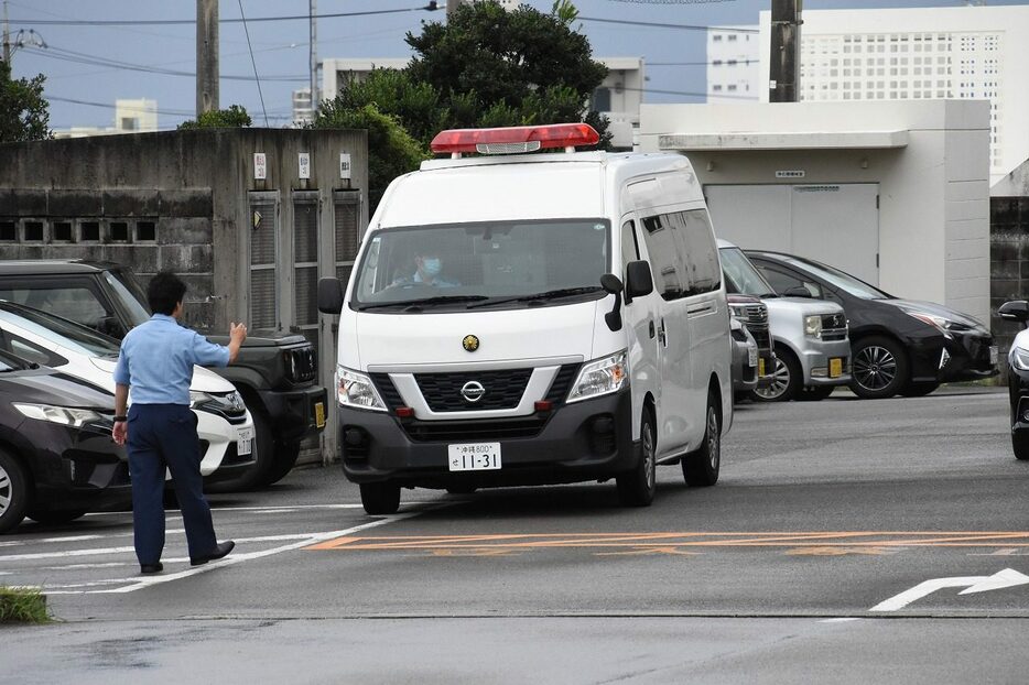 男を乗せ八重山署から那覇地検石垣支部に向かう警察車両＝25日、八重山署