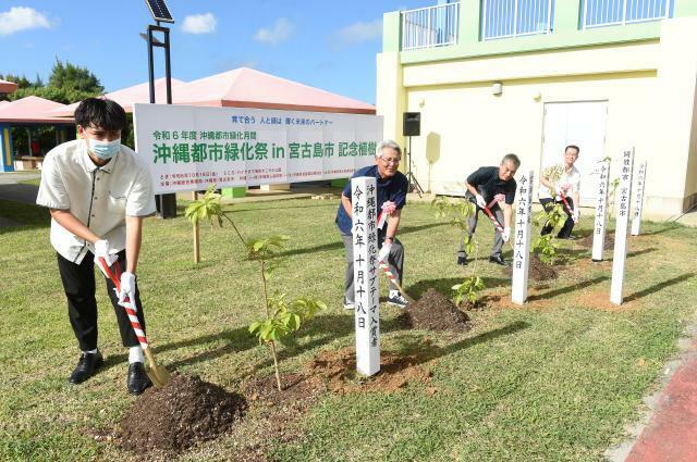 記念植樹を行う座喜味市長（左から2人目）ら関係者＝18日、パイナガマ海空すこやか公園