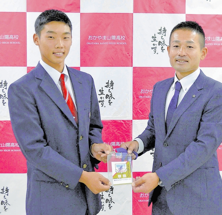 DeNAの藤田さん（右）から記念品を受け取る田内選手（岡山県浅口市で）