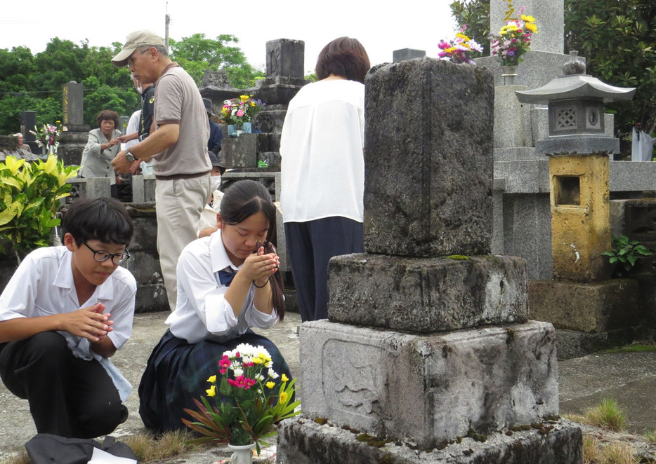 先祖の墓前で手を合わせる住民ら＝25日、鹿児島県喜界町