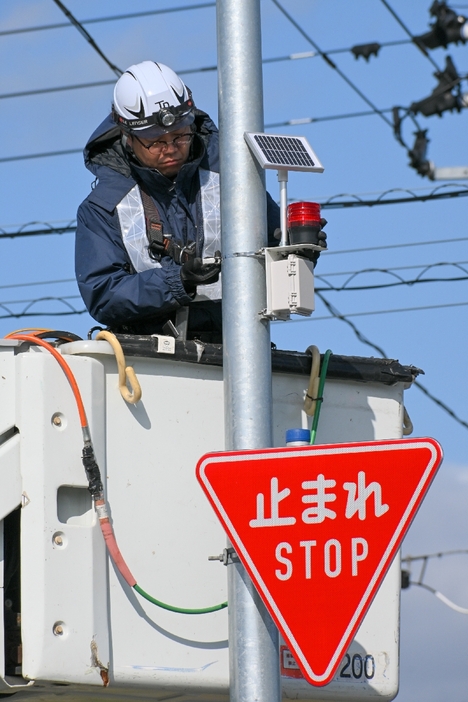 「旧柳沢駅交差点」の「止まれ」標識の上に設置された回転灯＝28日、六戸町