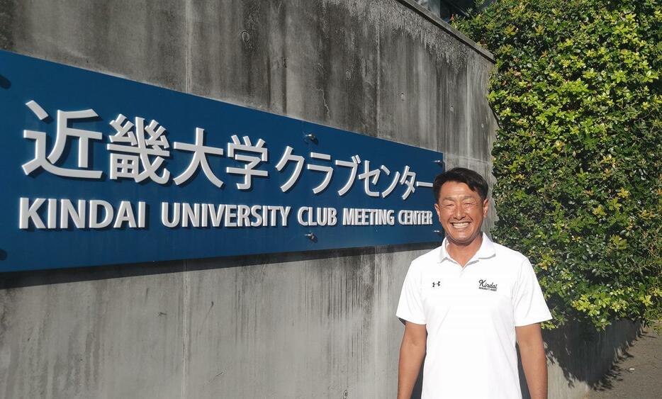 近畿大学ラグビー部で指導を始め、10シーズン目を迎える岡野干城ヘッドコーチ。大阪工大高（現・常翔学園）で 1年上だった神本健司監督を支え、まずは初の関西リーグ優勝を目指す。写真はデスクのあるクラブセンターの前で