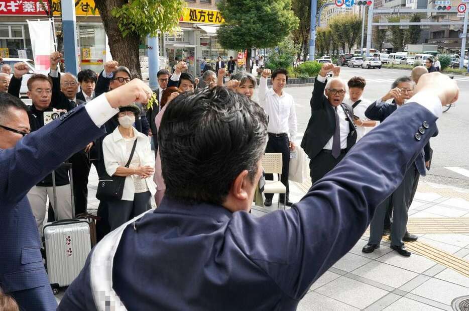 出陣式で拳を突き上げる候補者（手前）と支援者ら＝15日午前9時42分、大阪市北区（鳥越瑞絵撮影、一部画像処理しています）