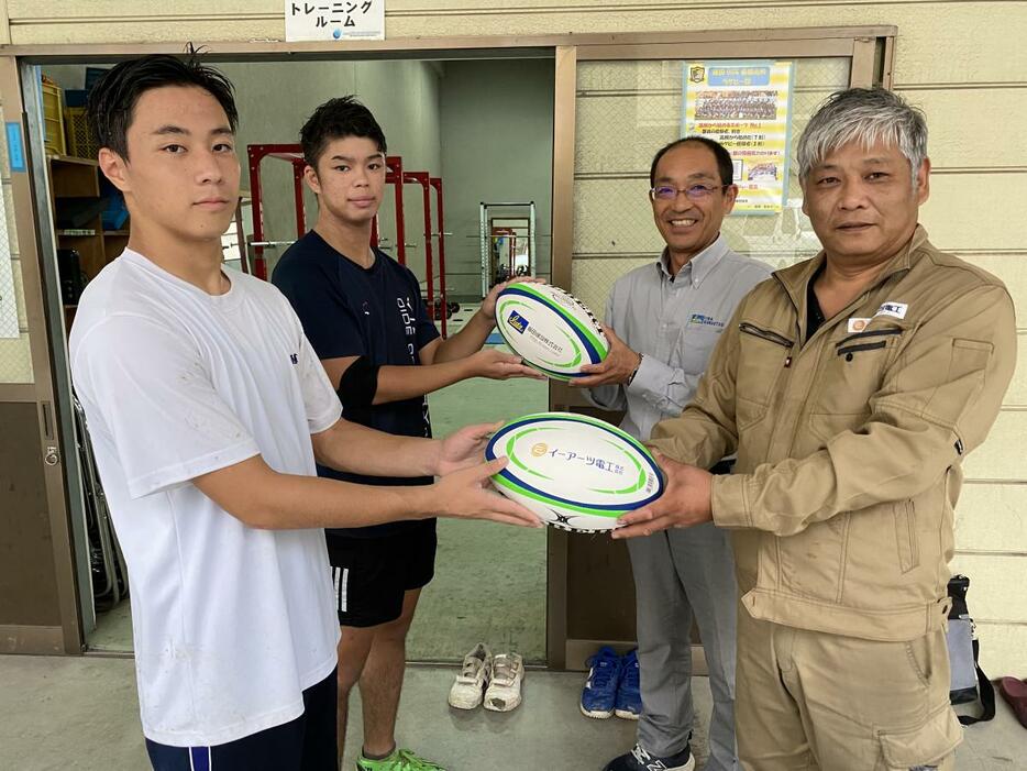 飯田OIDE長姫高校にラグビーボールを寄付するイーアーツ電工の木下敦夫社長（右前）と飯田建設の三石芳久社長（右奥）