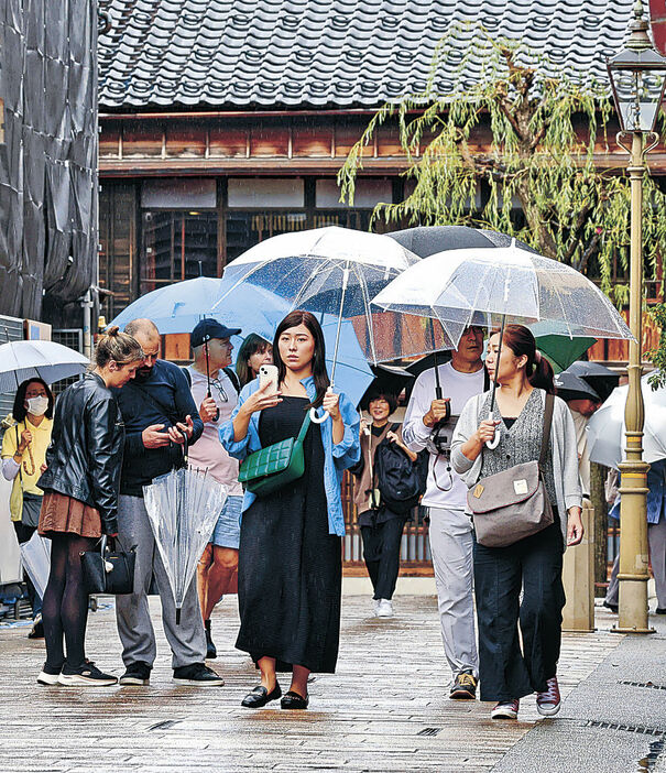 傘を手に散策する観光客＝１９日午前９時５０分、金沢市のひがし茶屋街