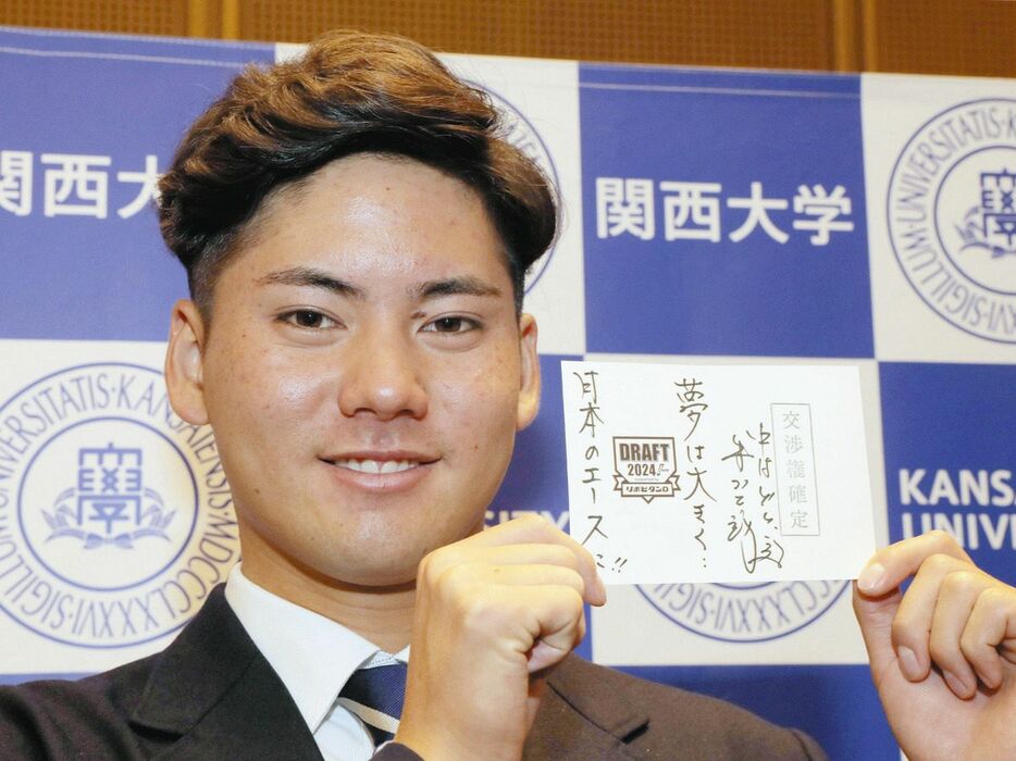 井上監督からのメッセージが書かれたドラフト会議の抽選くじを手に、笑顔を見せる関大・金丸夢斗