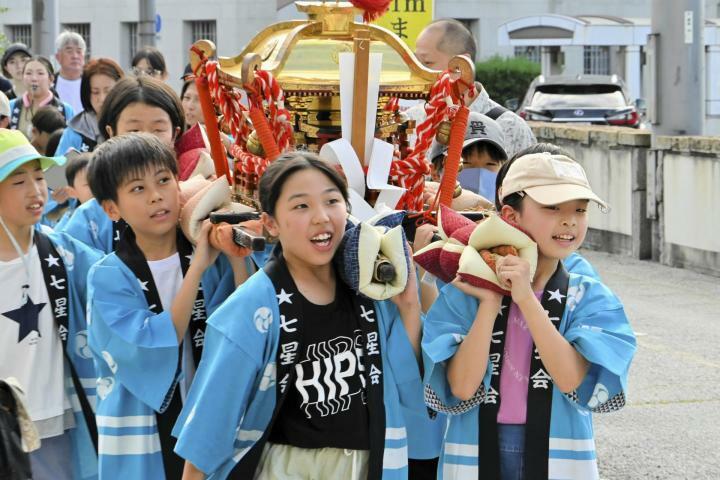 みこしを担いでまちを練り歩く子どもたち