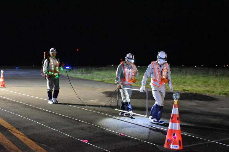 爆発で陥没し埋め戻された地点(中央右)の周辺で、他にも不発弾が埋まっていないか調べる作業員ら＝宮崎市の宮崎空港で2024年10月16日午後10時52分、塩月由香撮影