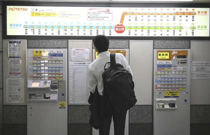 伊予鉄道松山市駅で値上げ後の運賃掲示を見上げる男性＝1日午前、松山市湊町5丁目