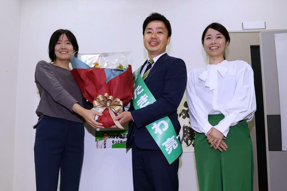 無投票再選が決まり、花束を受け取る滝沢亮氏（中央）＝１０月２０日午後５時すぎ　三条市西裏館１