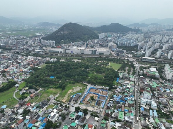 遠方から見下ろした金海市の鳳凰洞遺跡の全景。写真の中で下の方に青色のシートで区画したところが、伽耶時代の大型工事跡が出てきた発掘現場＝国立伽耶文化遺産研究所提供