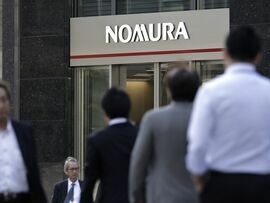 Pedestrians walk past a Nomura branch in Tokyo. Photographer: Kiyoshi Ota/Bloomberg