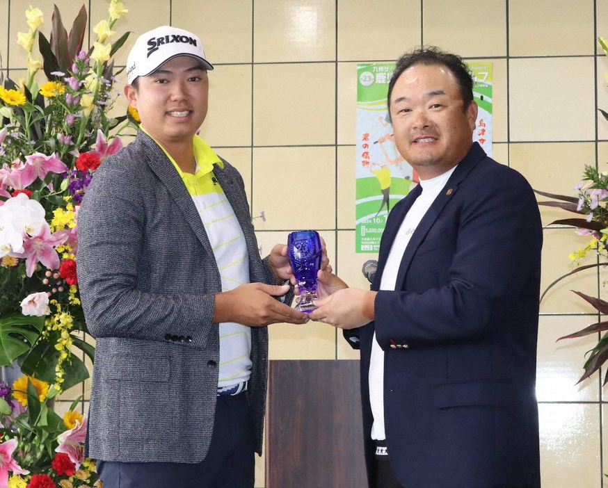 大会初優勝の出水田は九州プロゴルフ研修会の小田孔明副会長（右）から優勝杯を贈られる