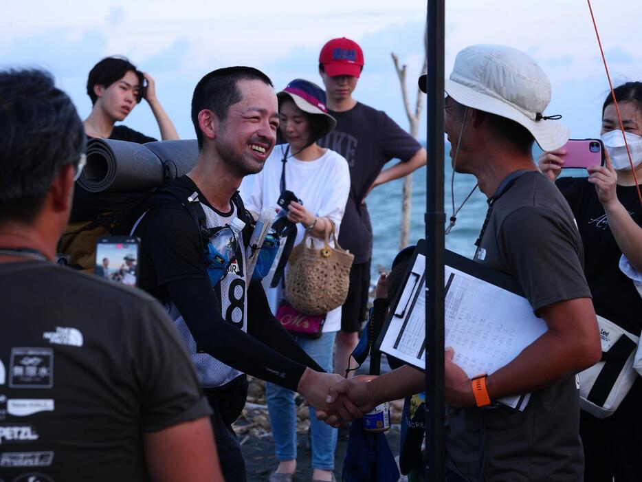 静岡市の大浜海岸でゴール。関係者に囲まれ、満面の笑顔を見せる蘆田さん（提供）