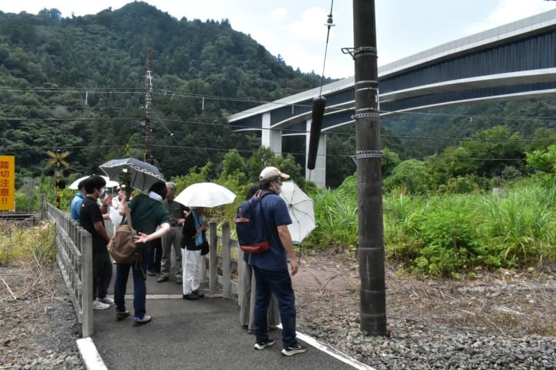 銃撃の現場となったトンネル方向を見つめる慰霊の集いの参加者。後方は高尾山