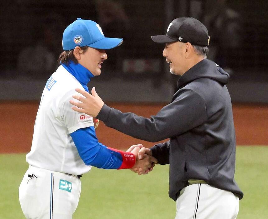 　試合後、新庄監督（左）と握手を交わし、勝利をたたえる吉井監督（撮影・伊藤笙子）